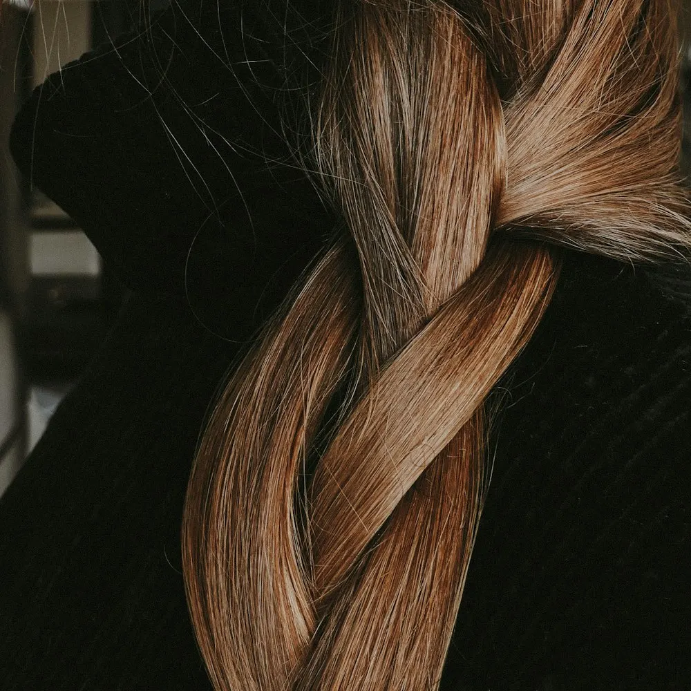 A loose braid falling over a dark sweater, lit from the side